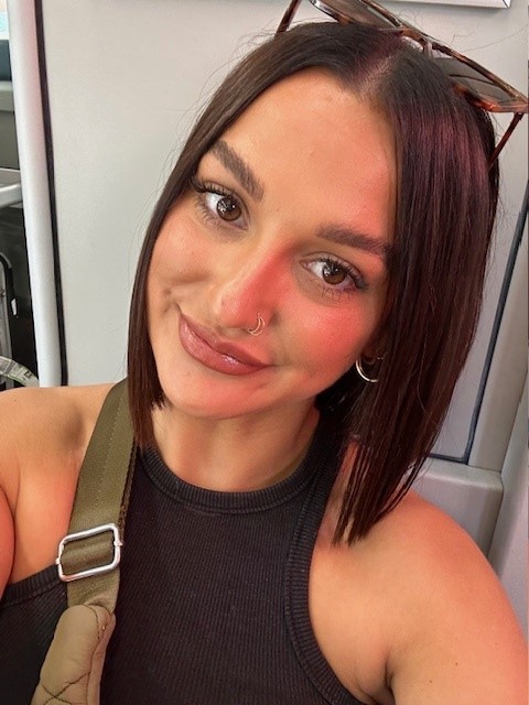 A young lady with sunglasses on the top of her head smiling