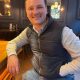 A young man sitting in a bar/restaurant smiling